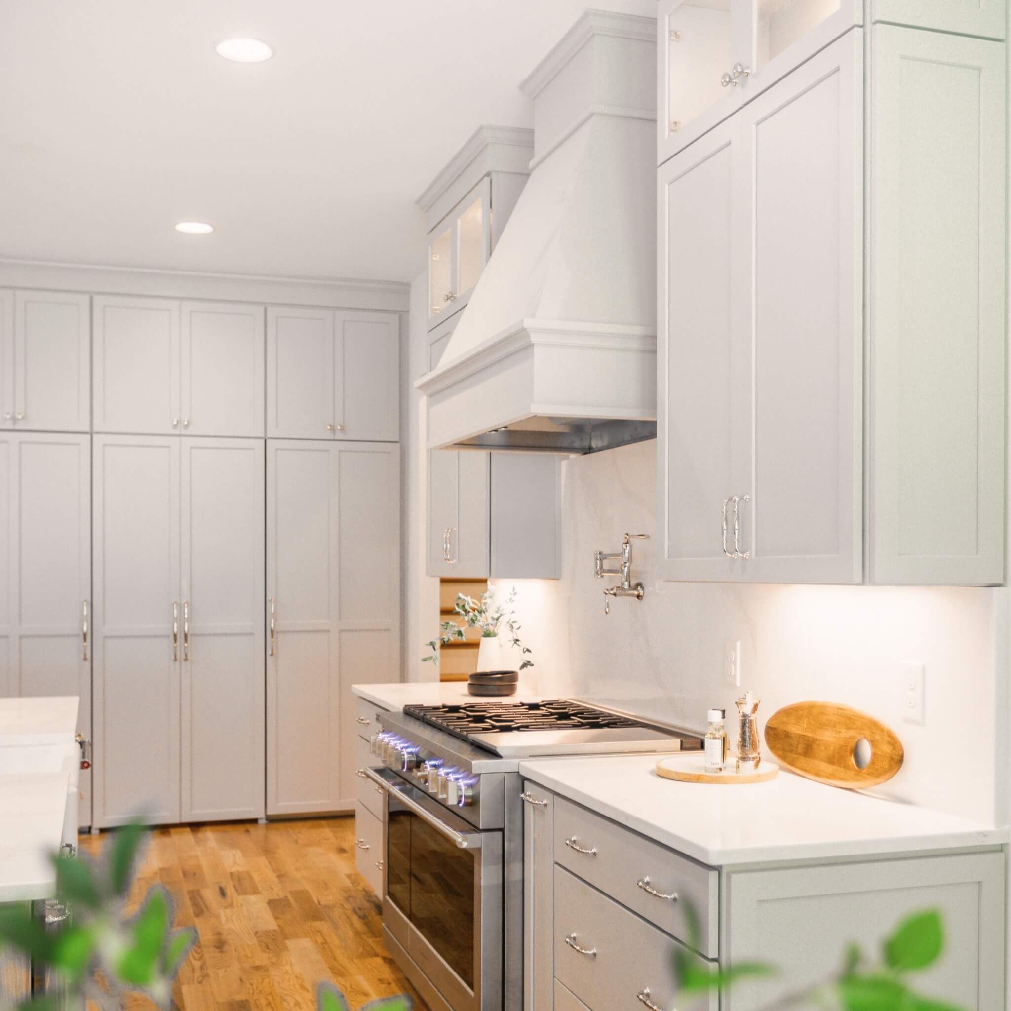 A beautiful all-white kitchen design with white painted cabinets and wood hood in a tonal, off-white hue.