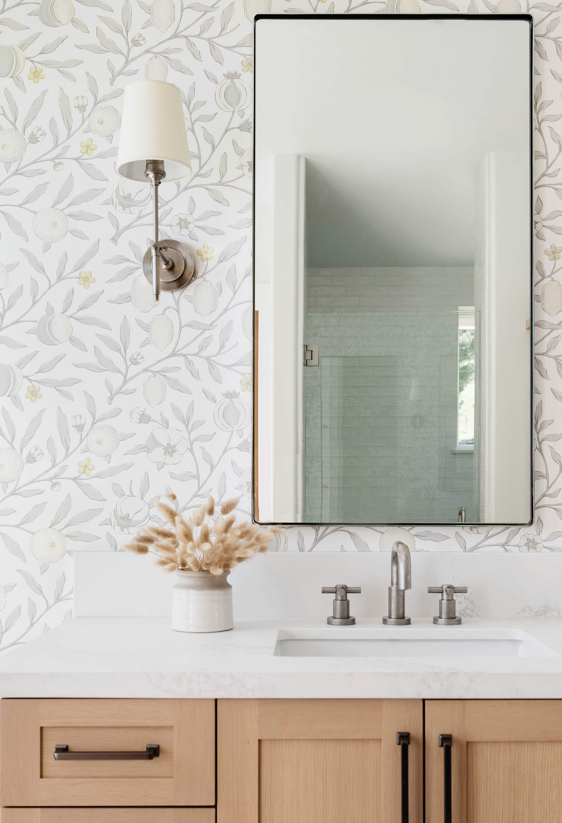 A luxurious bathroom design with light stained quarter-sawn oak cabinets paired with several luxurious details like designer wallpapers, micro framed vanity mirror and trendy hardware and fixtures.