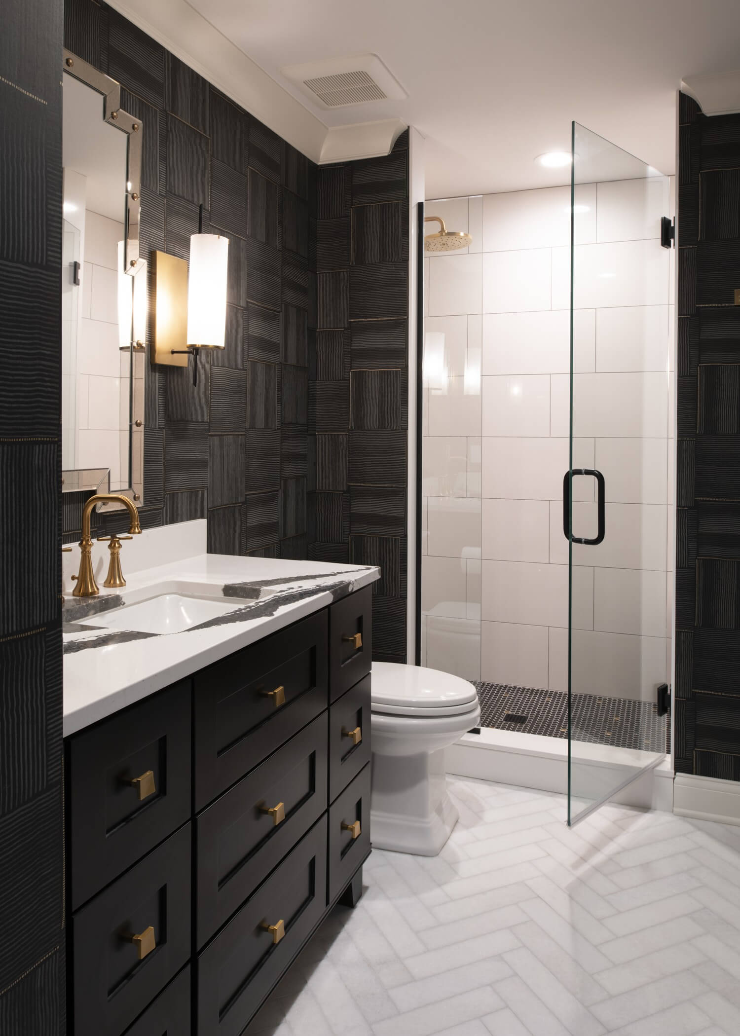 Dark and moody bathroom design featuring black bathroom vanity cabinets accented by warm brass cabinet pulls and fixtures. The custom cabinetry, abundant storage, and layered contrasts create a bold yet timeless bathroom aesthetic.
