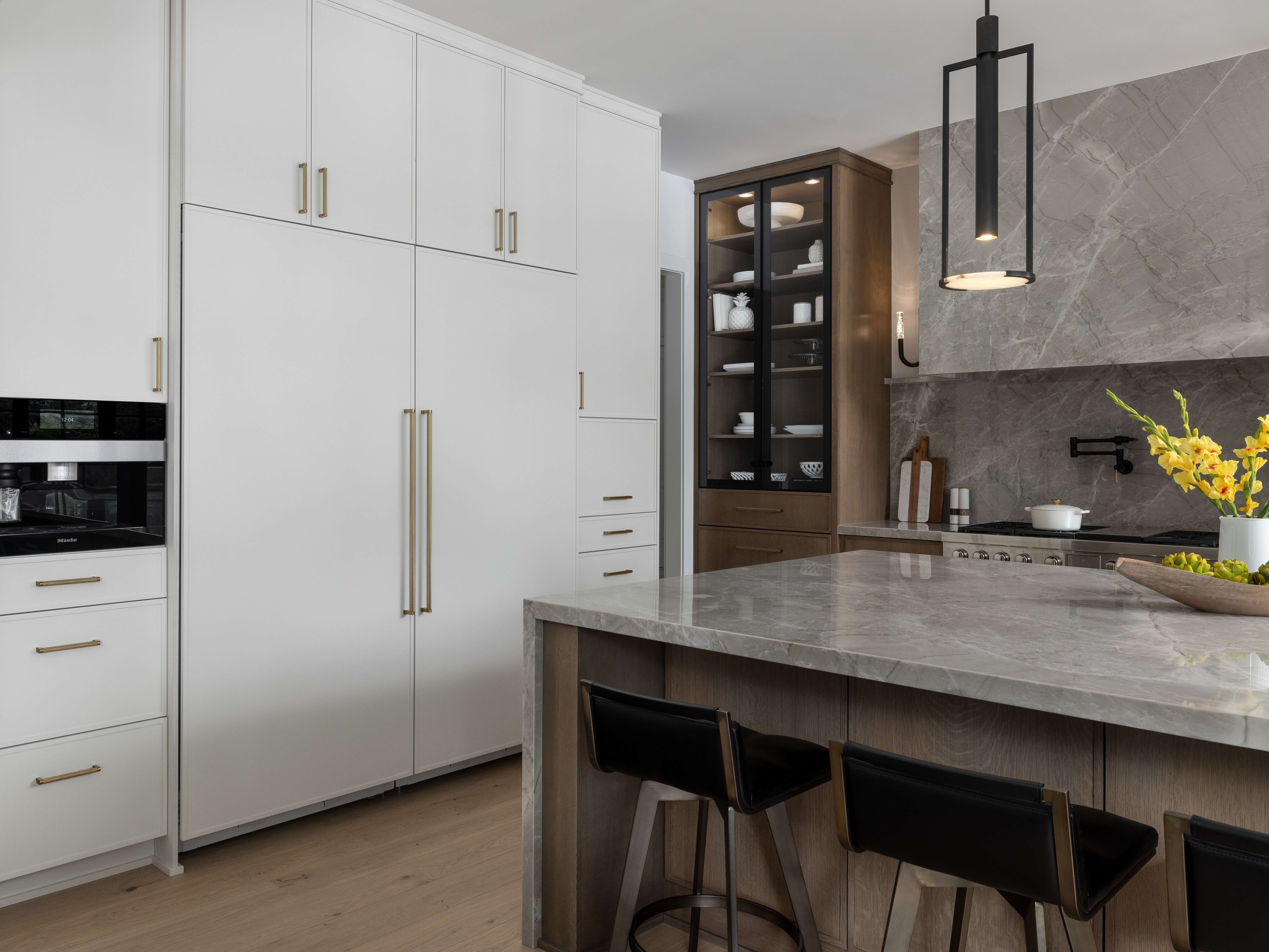 Two-tone kitchen cabinets feature crisp white painted slim shaker cabinetry paired with a warm wood-tone kitchen island for a clean, contemporary look. Sleek black cabinet hardware and modern pendant lighting add contrast while enhancing the kitchen's refined design.