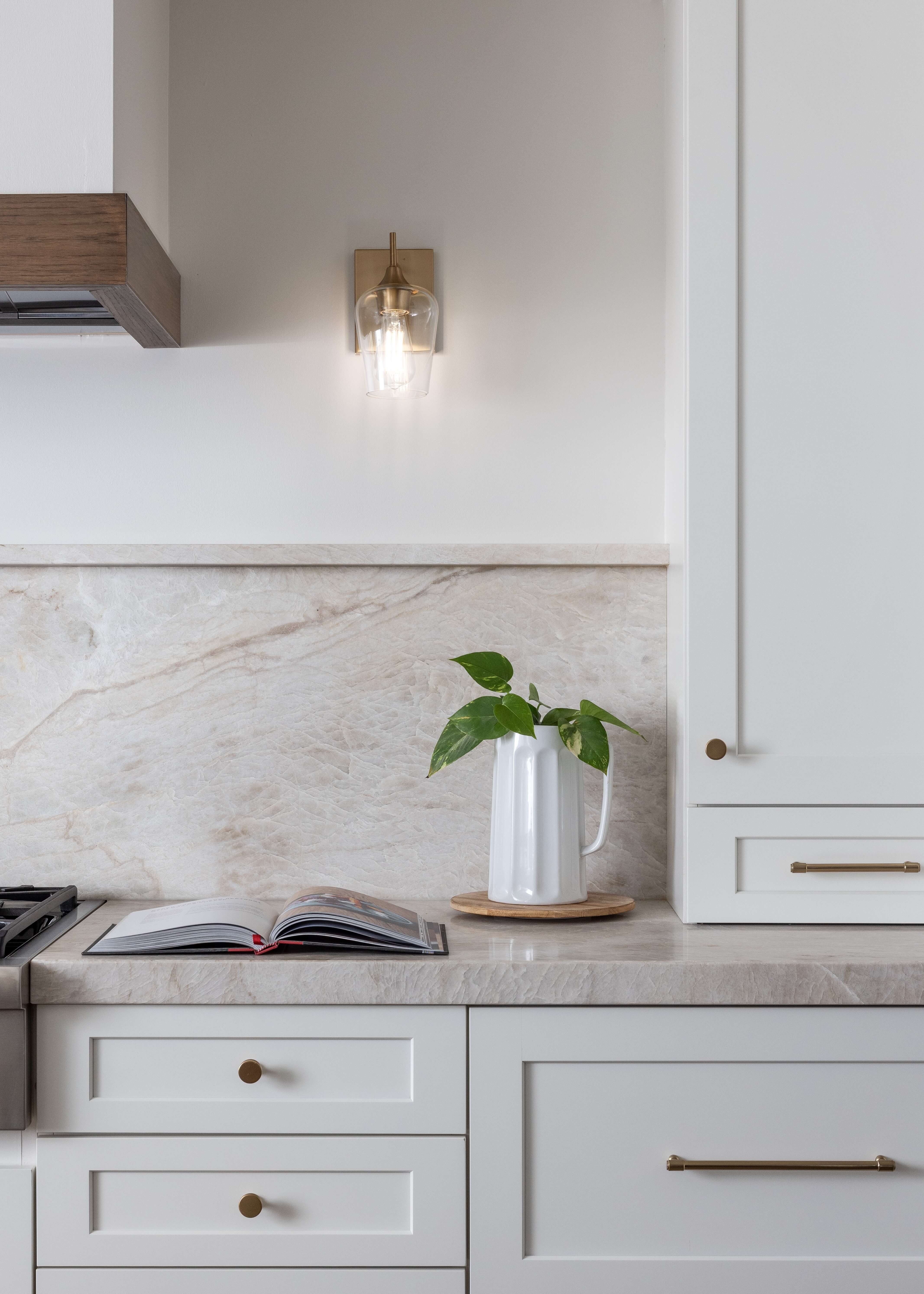 White painted shaker cabinets feature a designer mix of round cabinet knobs and modern brushed brass pulls for a layered, custom look. Clean cabinetry lines, warm metallic accents, and timeless details create an elegant and inviting kitchen design.