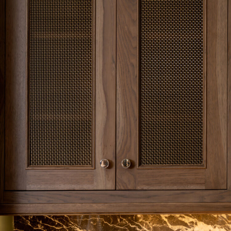 This kitchen cabinet features decorative wire mesh cabinet door inserts in antique brass that add texture and artisan character to the cabinetry. The mesh inserts have a tight weave pattern and provide visual interest.